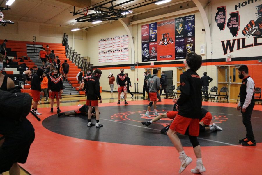 The team warms up in the main gym, using the time before the match to lightly jog, stretch, or scout their opponents.