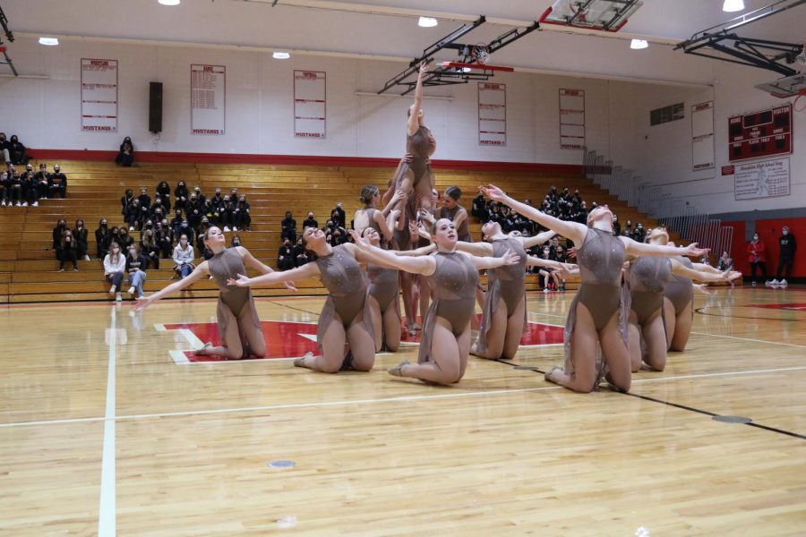 Senior Emma Sauers is lifted as the surrounding dancers kneel, arms extended facing high above.