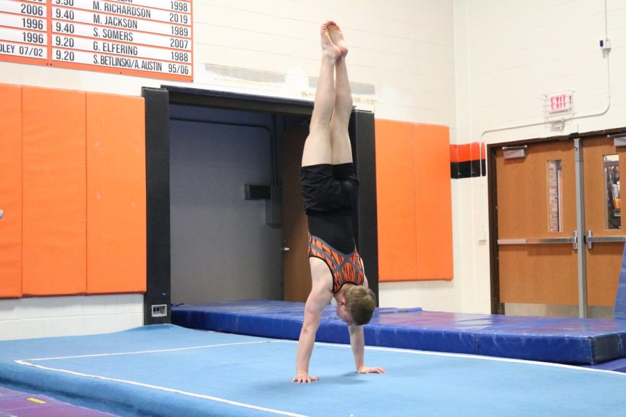 Varsity gymnast Grady Georgia performs a handstand as part of his floor routine. He finished in a tie for first in floor with a total of 8.700 points.