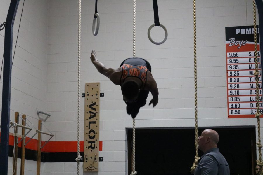 JV gymnast Anthony McClendon completes his still rings routine with a fly away. He also competes on the high bar and pommel horse.