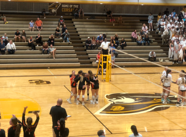 As spectators look on, the team huddles together in celebration following a point scored against the Carmel Corsairs.