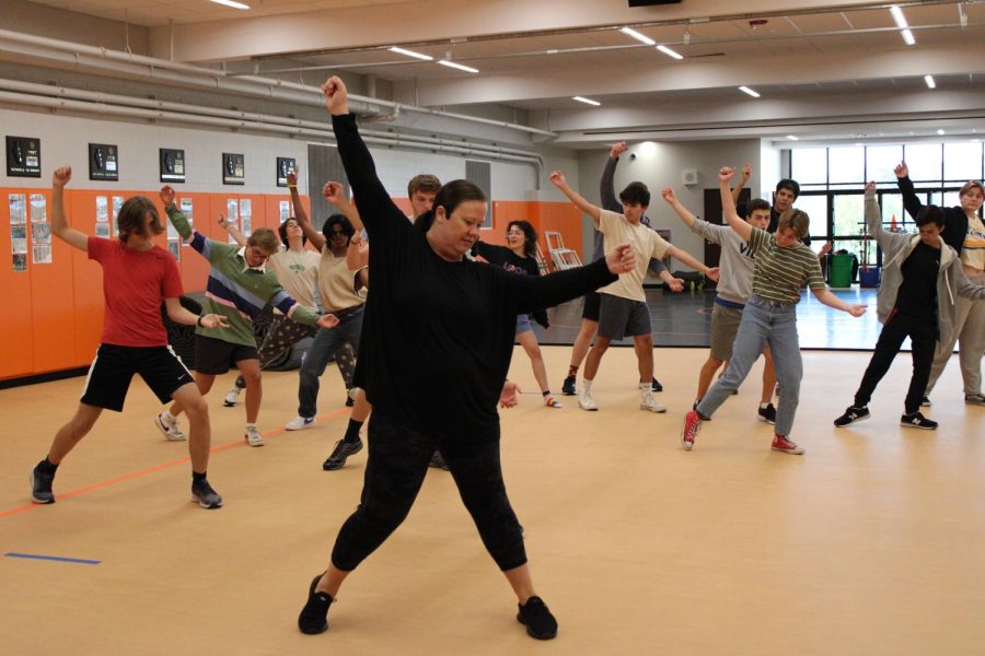 Mrs. Brown, the dance director, shows off her air guitar skills while the cast tries to recreate her dance moves. 
