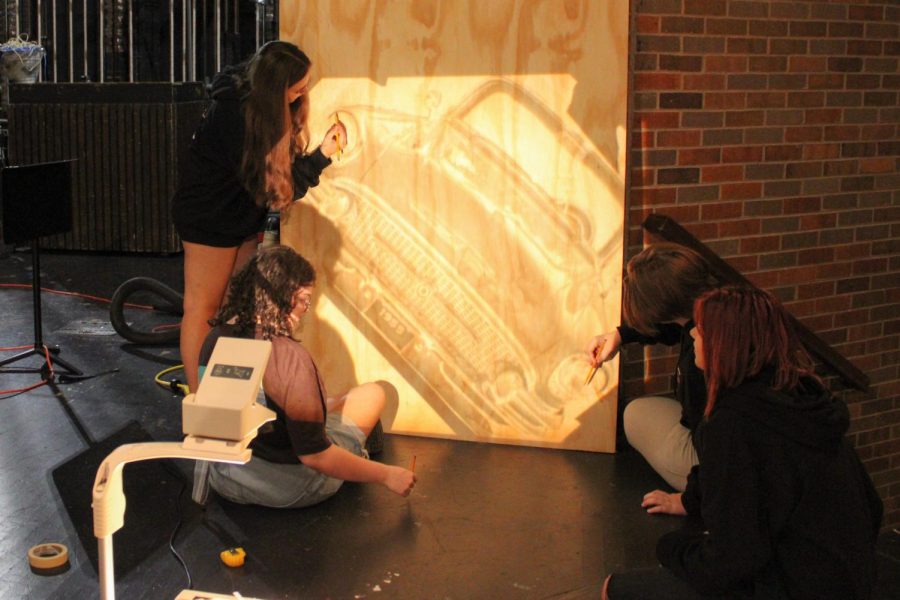 Crew members outline the projection of a 50s style car, creating one of the main props for the show.