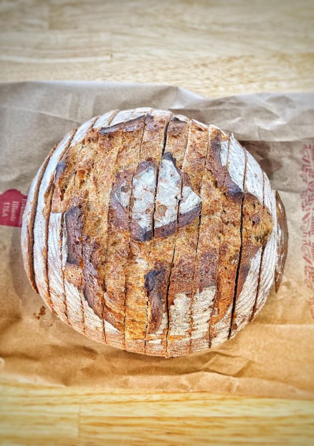 A loaf of freshly sliced bread awaits a buyer at Hewn Bakery. The country round loaf has a nutty flavor, crispy crust, and a chewy texture on the inside.