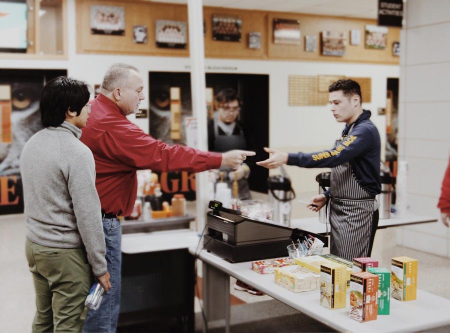 Before first period, juniors Haziel Morales (background left) and Xavier Granados (behind the counter) serve a regular customer, Mr. Mike Mansell, as another regular customer, senior Alex Delatorre, waits in line. 
