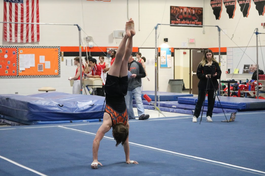 Senior Josh King sticks his landing and holds a handstand, earning him an 8.30 on the floor exercise for the varsity team.