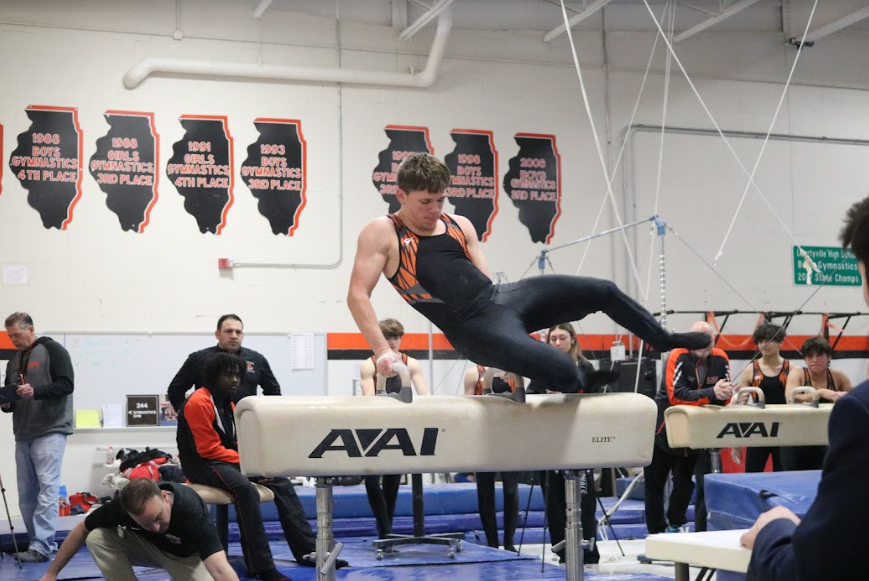 Junior Micah Hafen flies over the handlebars, achieving a 6.0 on the pommel horse for the JV team.
