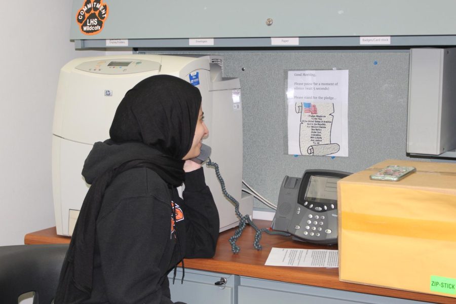 Senior Fatma Elmenshawy in the main office reads the pledge to the school over the loudspeaker in the beginning of second period.