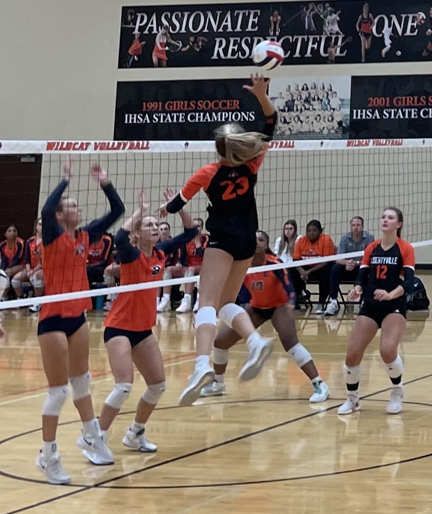 Sophomore Avery Maddux (23) slams a spike across the net to her opponents, with senior Jaimie Marquardt (12) backing her up.
