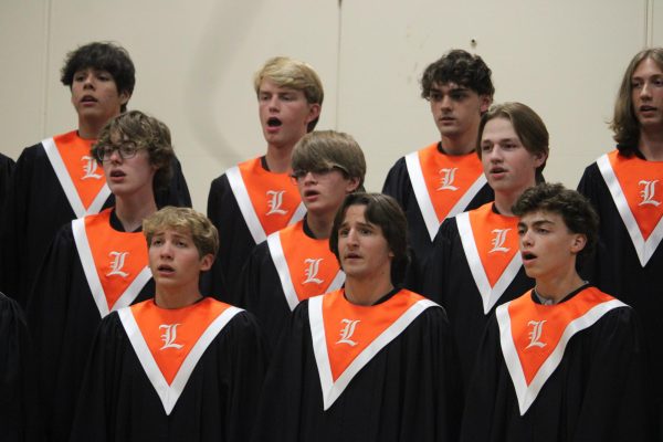 Male members of the Concert Choir sing “All The Way Home” by Sarah Quartel. Their orange neckerchiefs symbolize that they are upperclassmen.