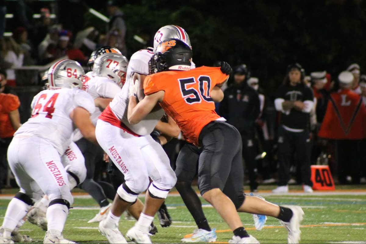 Senior Owen McGrory (50), an offensive and defensive lineman, battles against an opposing player for Mundelein. Later in the season, McGrory advised future players to “cherish it. It’s not about winning or losing. It’s about the brothership, the bond.”
