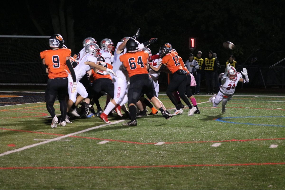 Mundelein outside linebacker and wide receiver Maddux Hermestroff (24), a junior, dives for the ball as the two teams converge on one another in the center. For Libertyville, juniors Josh Holst (9) and Rhett VanBoening (64) keep Mundelein at bay, along with senior Luka Nikolich (13).