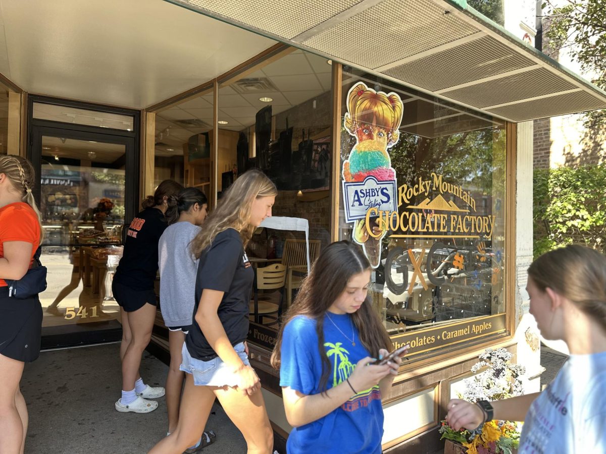 The girls cross country team paints Rocky Mountain Chocolate Factory’s main windows in the homecoming´s theme.