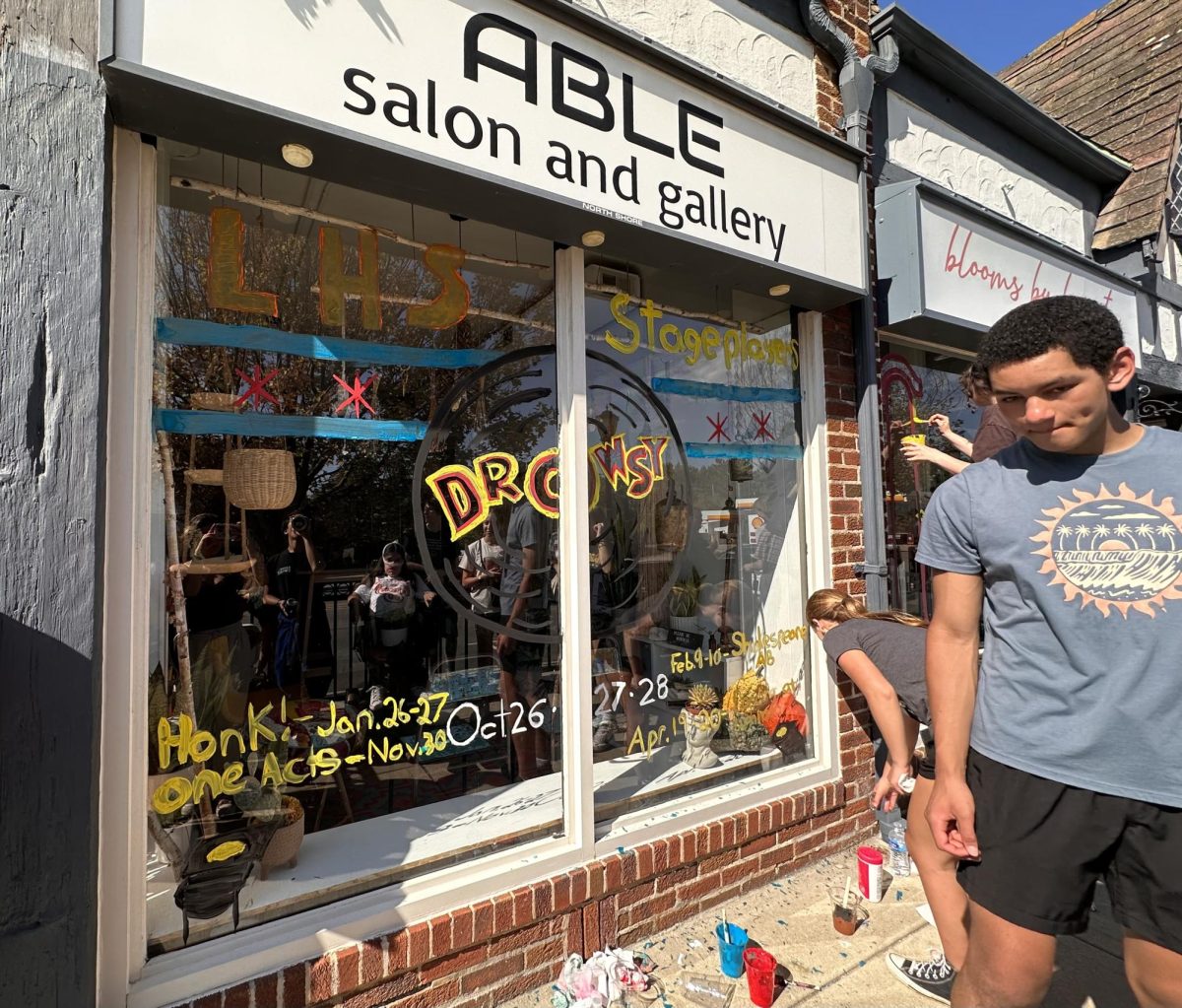 Stageplayers paint the Chicago flag and upcoming events they are involved in Able’s Salon and Gallery window.