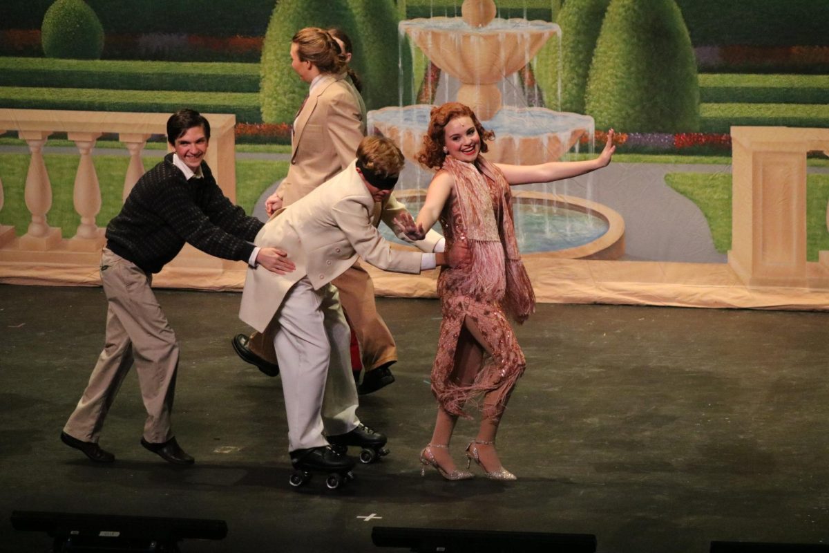 Senior Louie Perry glides across the stage, blindfolded and on roller skates, a feat that took a lot of practice. Pictured in this scene, Janet, the bride, manages to find Robert, who is blindfolded so that he would not see his bride on the day of the wedding.