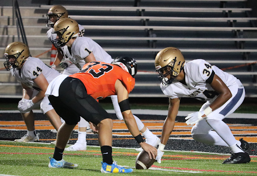 During the varsity football team’s season opener against Lemont, sophomore Jack Treutelaar (33), a long snapper and middle linebacker, sets up for a play wearing his blue and yellow cleats from the Alex’s Lemonade Stand Foundation, a symbol of the fundraising he did for the organization.