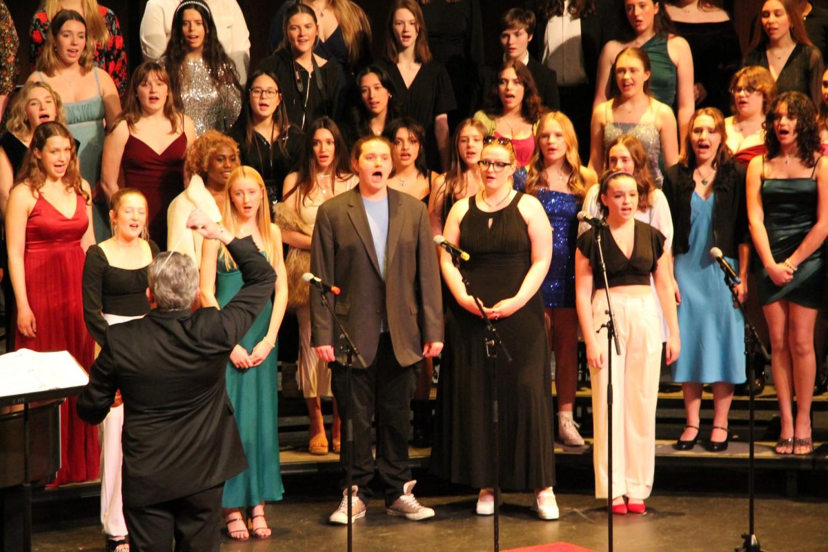 The LHS choir, conducted by Dr. Jeff Brown, performs “Morning Glow” from “Pippin”. Senior soloists (front row, from left) Nicole Smith, Caroline Scott, Peter Eriksen, Lanthe Bryson, Jordana Block-Terson. “The act of singing with others – this is a thing that we're all doing at the same time together,” Dr. Brown said. “I think it's a good thing and that it brings a lot of joy to people's lives.” (Caption by Ash Magalhaes