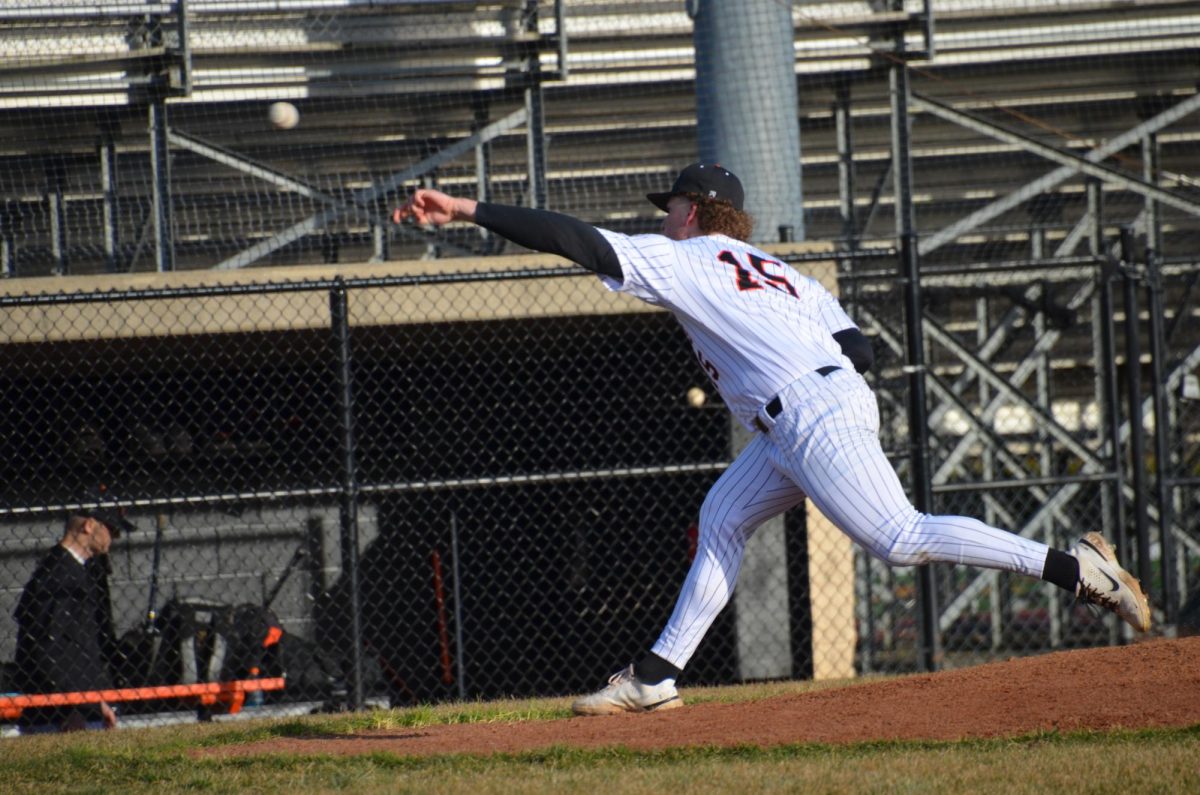 Junior Josh Holst (15) fires the ball to home plate, rounding out the first inning with a strikeout. 