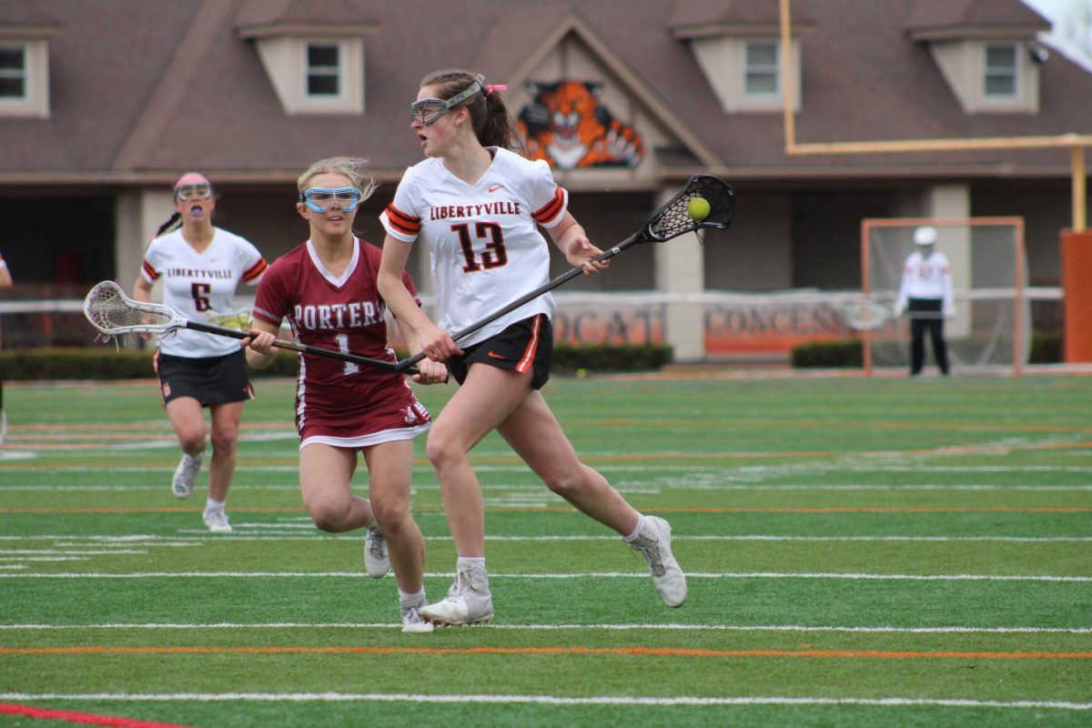 Cradling the ball, senior Sophia Weick (13) speeds past Lockport's junior defender Sabina Bukowski (1) to get a shot on the goal. Weick has been on varsity all four years of high school and is one of the team captains.