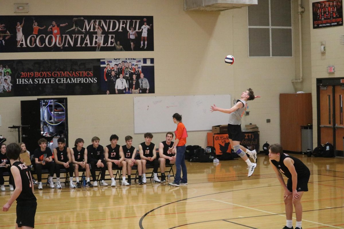 Sophomore libero and outside hitter Jackson Kern (11) serves in the first set. 