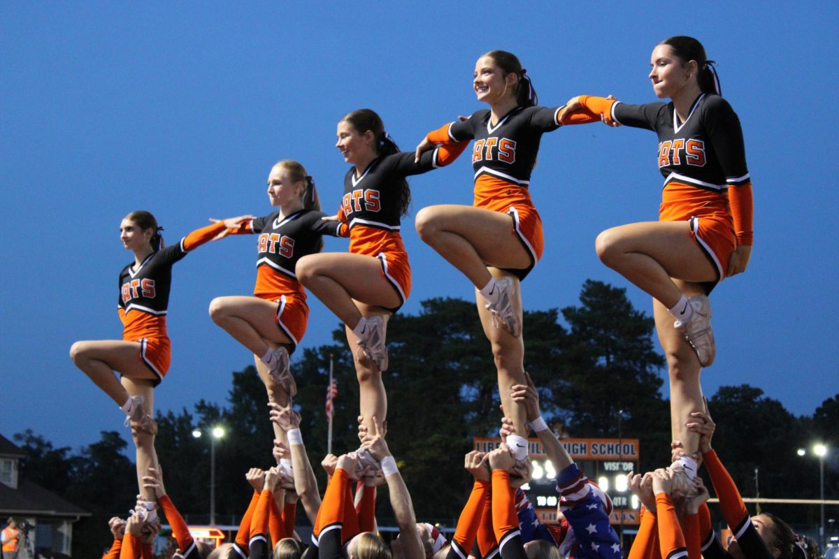The cheerleaders highlight one of their stunts prior to the game to energize the crowd. From left to right, sophomore Madi O’Donnell, seniors Devyn Gordon, Mel Carroll, Scarlett Meyer and Kaileigh Sullivan. The cheer team also leads chants, and performs stunts on the sidelines throughout the game.