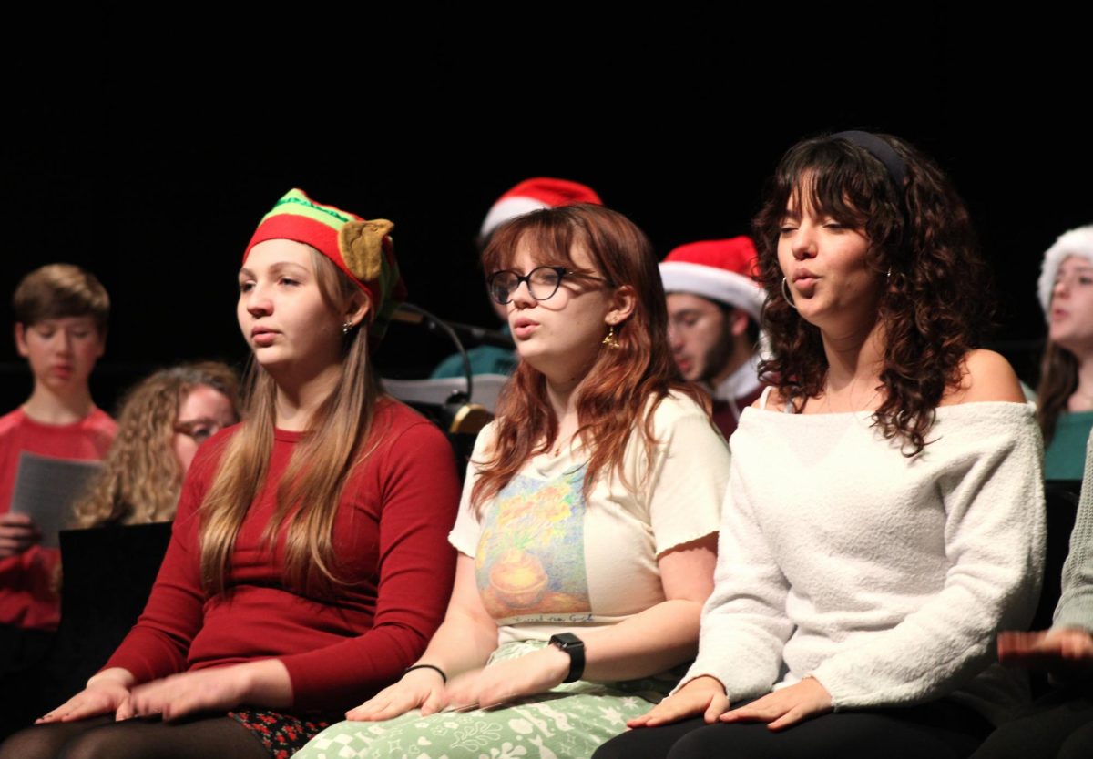 Seniors (from left to right) Zoe Mueller, Marley Herchenbach and Ella Globerger sit in front as they perform "White Winter Hymnal" by Pentatonix. This performance features skilled hand movements that accompany the voices of the Master Singers group.