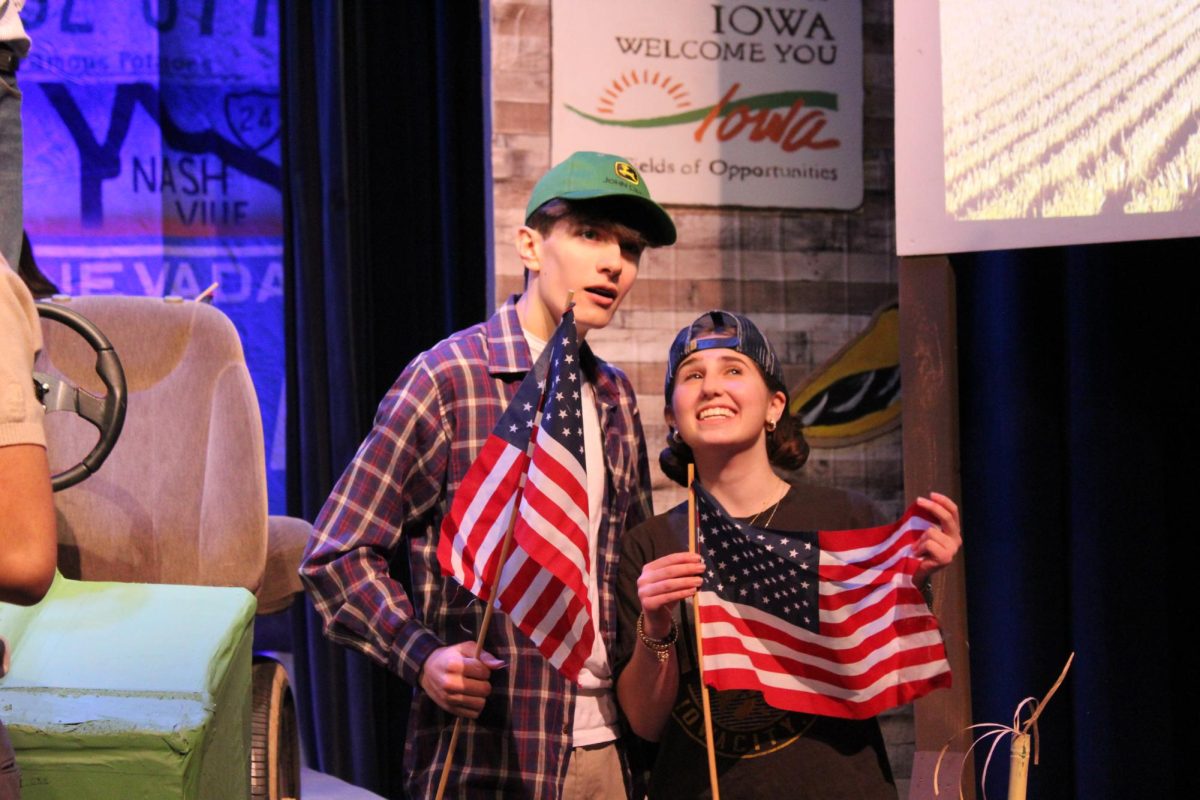 The duo of mechanics (left to right), freshman Nick Chalifoux and sophomore Amalia Rappa, pose with the American flag while Adult Don completes his monologue about the best trip ever. 