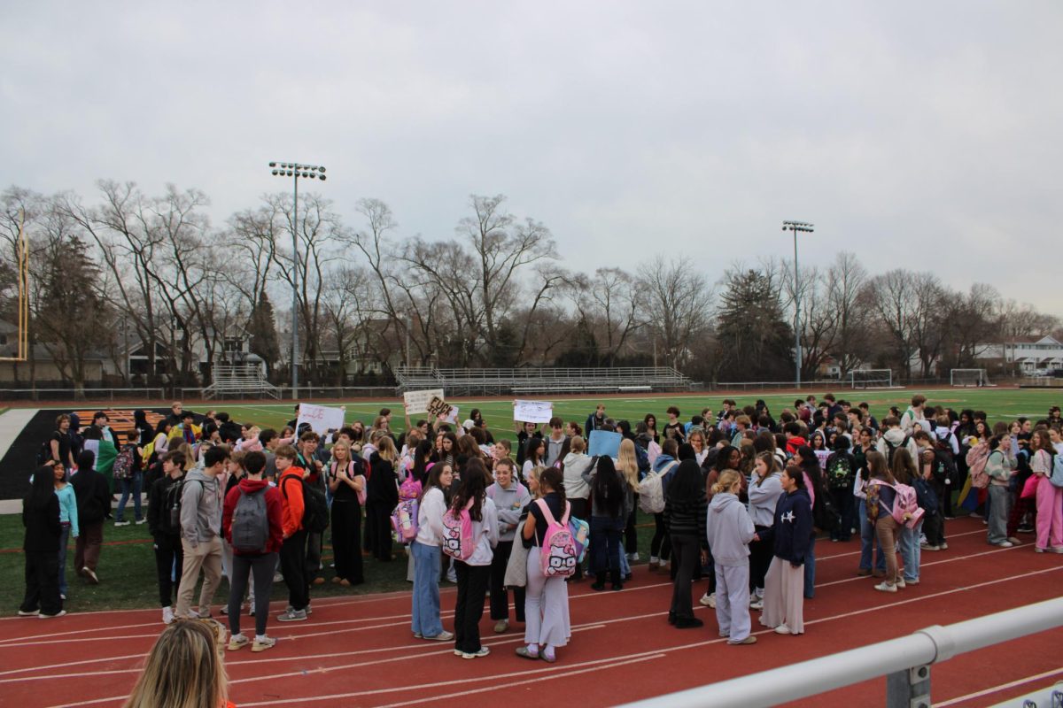 Students gather on the football field to begin their walkout in protest against Immigration and Customs Enforcement. Many are seen holding up signs, talking to their peers and ready to make a statement.