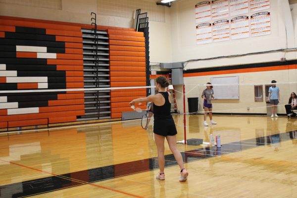 Junior Kira Dolph sets up for an underhand serve. Dolph, a skilled varsity player, demonstrates excellent focus and precision throughout the match.