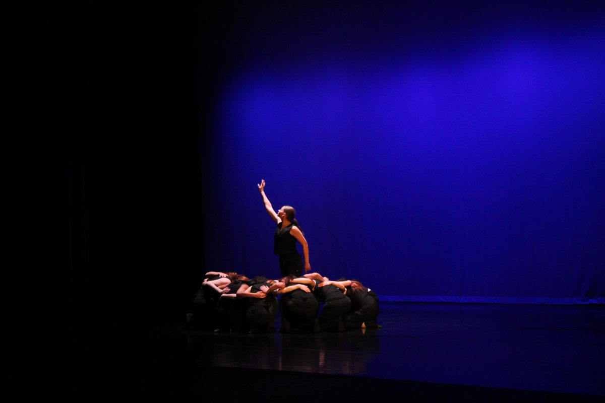 A dancer reaches toward the sky at the conclusion of Mosaic, choreographed by Emma Dillon, moments before the stage fades to black.
